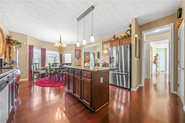 kitchen featuring decorative light fixtures, a center island, stainless steel appliances, a chandelier, and dark wood-style flooring