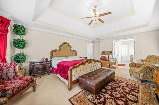 bedroom featuring a raised ceiling, ceiling fan, carpet flooring, and crown molding