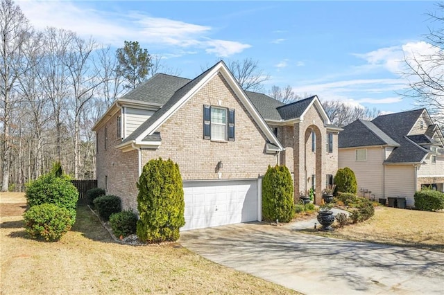 view of home's exterior with an attached garage, brick siding, driveway, and a yard