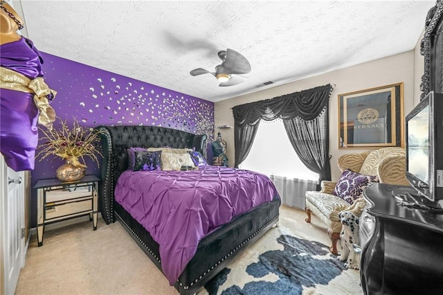 carpeted bedroom featuring visible vents, wallpapered walls, a textured ceiling, and a ceiling fan