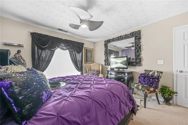 bedroom with visible vents, a textured ceiling, carpet flooring, and a ceiling fan