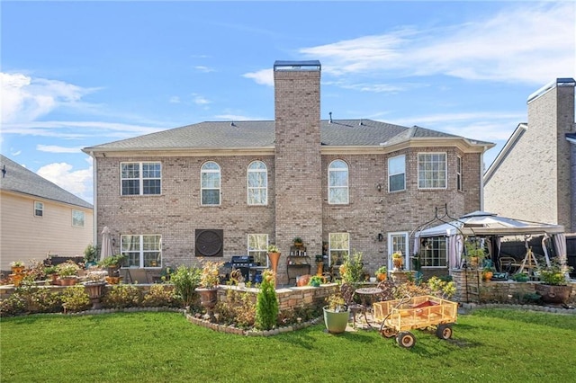 rear view of property with a gazebo, brick siding, and a yard