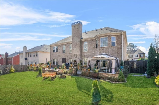 back of house featuring a lawn, a chimney, a fenced backyard, and brick siding