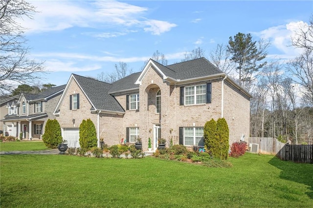 view of front of house with brick siding, an attached garage, a front lawn, and fence