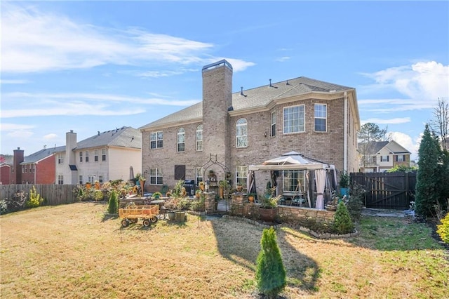 back of property with brick siding, a lawn, a chimney, and fence