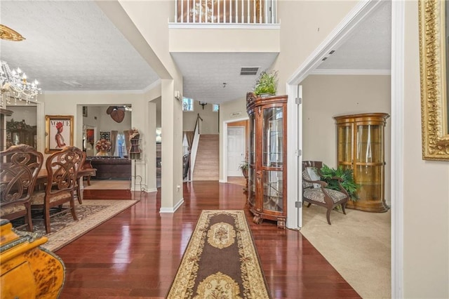 foyer with a chandelier, crown molding, stairs, and wood finished floors