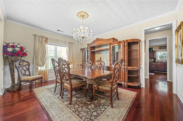 dining area with a wainscoted wall, a notable chandelier, dark wood finished floors, and visible vents