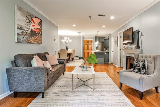 living room with a chandelier, ornamental molding, and light hardwood / wood-style flooring