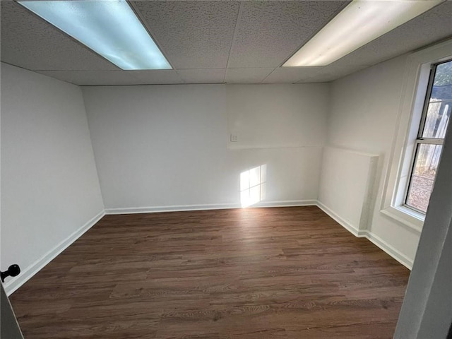 spare room featuring a drop ceiling and dark wood-type flooring