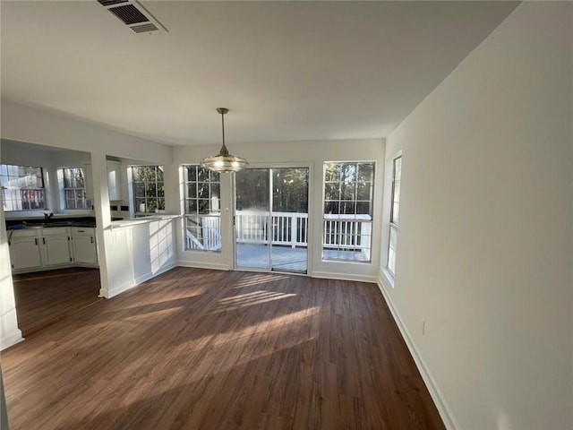 unfurnished dining area with dark wood-type flooring