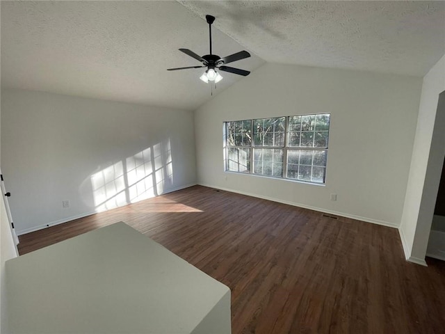 unfurnished living room with vaulted ceiling, ceiling fan, dark hardwood / wood-style floors, and a textured ceiling