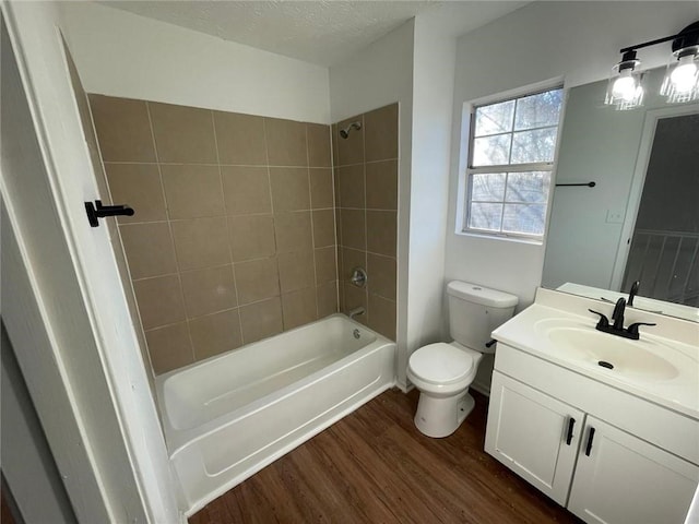 full bathroom featuring vanity, a textured ceiling, hardwood / wood-style floors, toilet, and tiled shower / bath