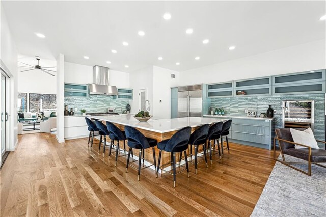 kitchen featuring sink, a kitchen bar, built in refrigerator, a large island, and light hardwood / wood-style floors