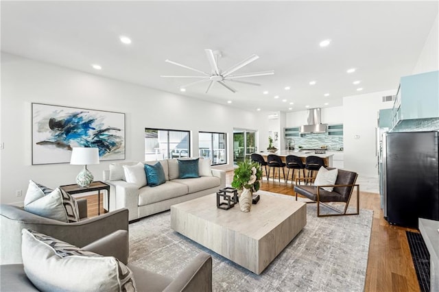 living room with light wood-type flooring, recessed lighting, and a ceiling fan