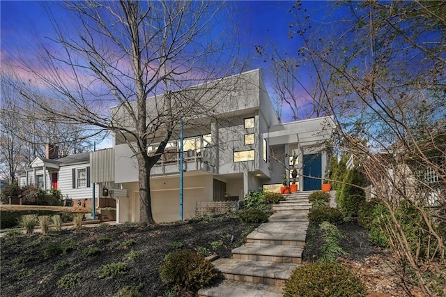 view of front facade featuring stairs, a balcony, and stucco siding