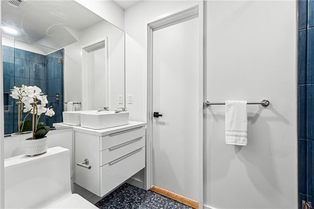 full bathroom featuring a tile shower, vanity, and toilet