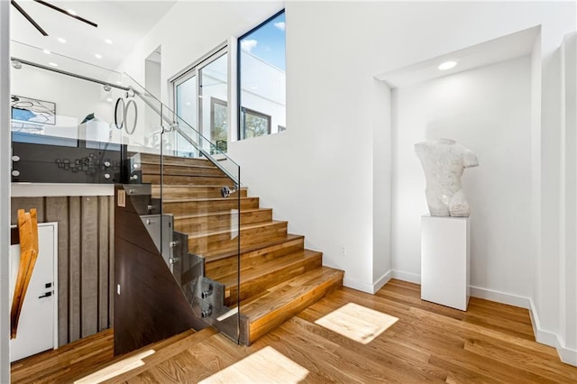 stairway with wood finished floors, baseboards, and recessed lighting