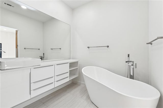 full bathroom with double vanity, a soaking tub, recessed lighting, and baseboards