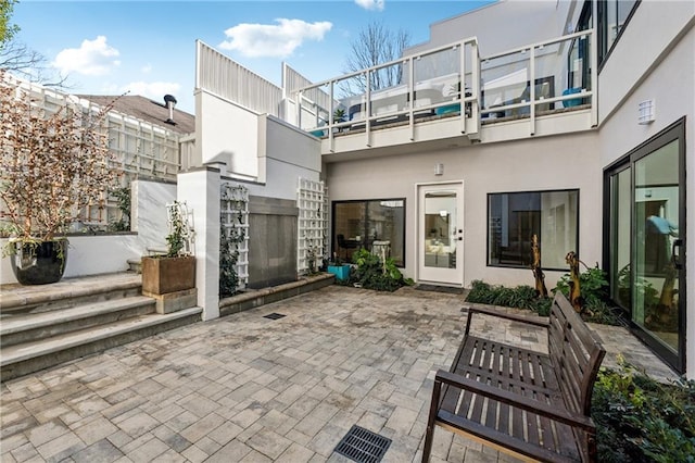 rear view of property featuring a patio, a balcony, and stucco siding