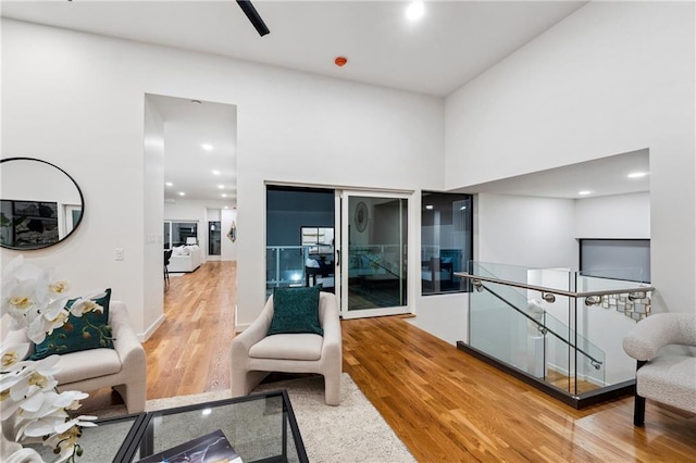 living area featuring light wood finished floors, an upstairs landing, and a towering ceiling