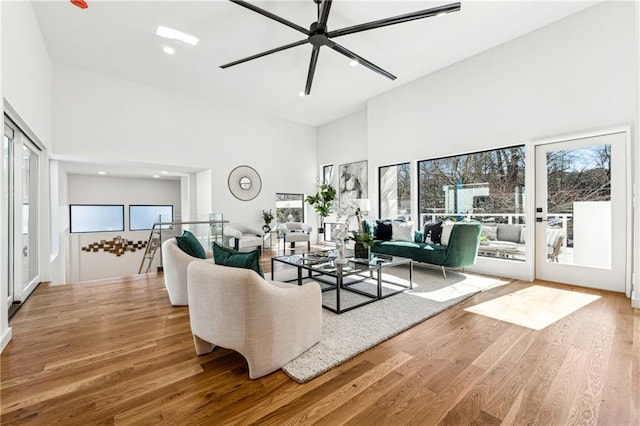 living room with a towering ceiling, wood finished floors, a ceiling fan, and recessed lighting