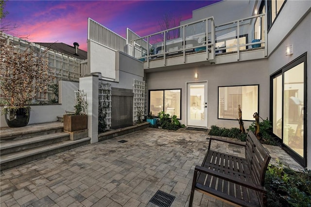 patio terrace at dusk featuring a balcony