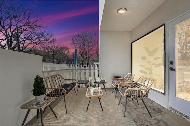 patio terrace at dusk featuring a balcony