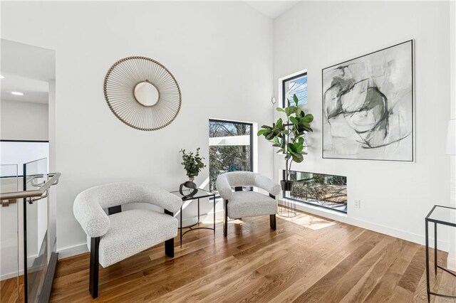 living room with hardwood / wood-style flooring, a towering ceiling, and ceiling fan