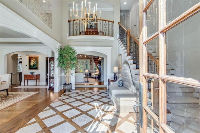 entryway with a high ceiling, an inviting chandelier, french doors, and crown molding