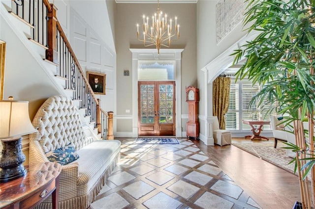 entryway featuring plenty of natural light, a towering ceiling, french doors, and an inviting chandelier