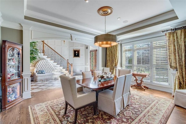 dining area with hardwood / wood-style floors, a raised ceiling, and ornamental molding