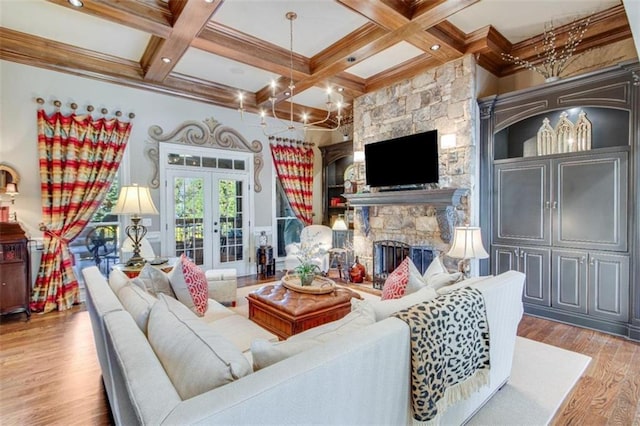 living room with french doors, coffered ceiling, light hardwood / wood-style flooring, beamed ceiling, and a stone fireplace