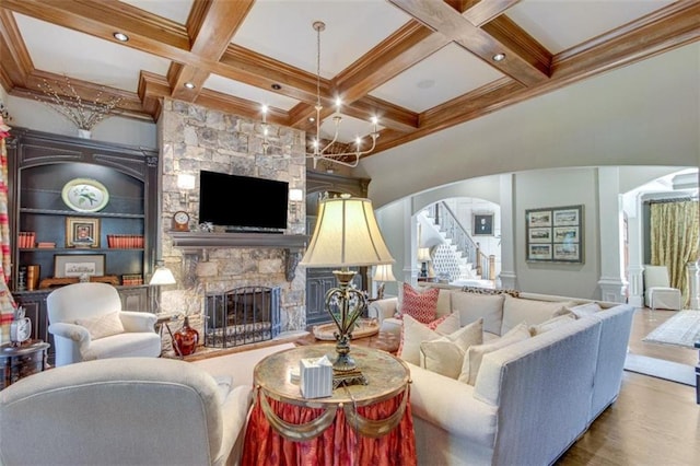 living room with hardwood / wood-style flooring, a stone fireplace, beamed ceiling, and coffered ceiling