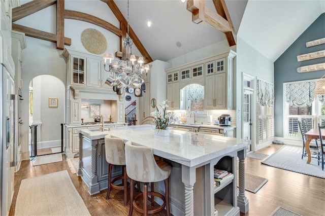 kitchen with high vaulted ceiling, a kitchen island, hanging light fixtures, and light hardwood / wood-style flooring