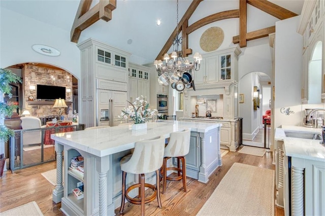 kitchen with a center island, high vaulted ceiling, decorative light fixtures, and light hardwood / wood-style flooring