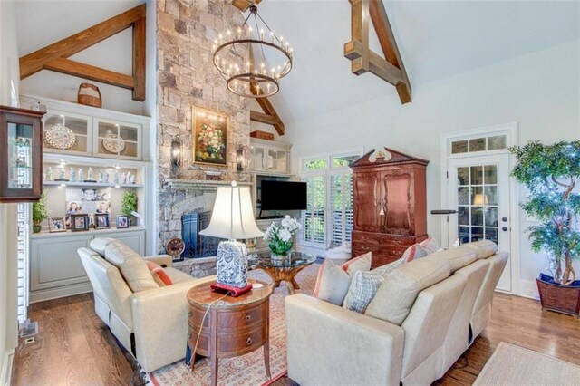 living room with hardwood / wood-style floors, high vaulted ceiling, a fireplace, a notable chandelier, and beam ceiling