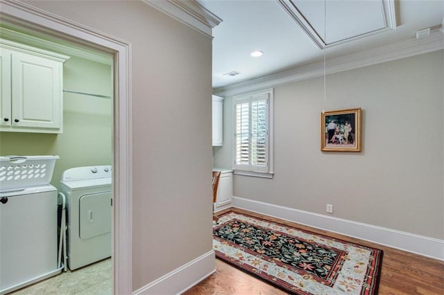 laundry room featuring light hardwood / wood-style floors, cabinets, independent washer and dryer, and crown molding