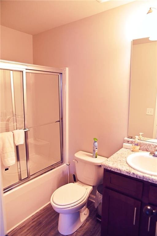 bathroom with toilet, shower / bath combination with glass door, wood finished floors, and vanity