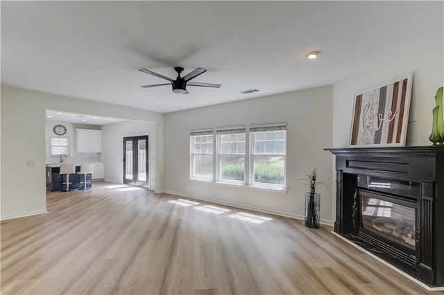7653 Legacy Rd, Flowery Branch, GA 30542 - unfurnished living room featuring a glass covered fireplace, ceiling fan, light wood-style flooring, baseboards, and a sink