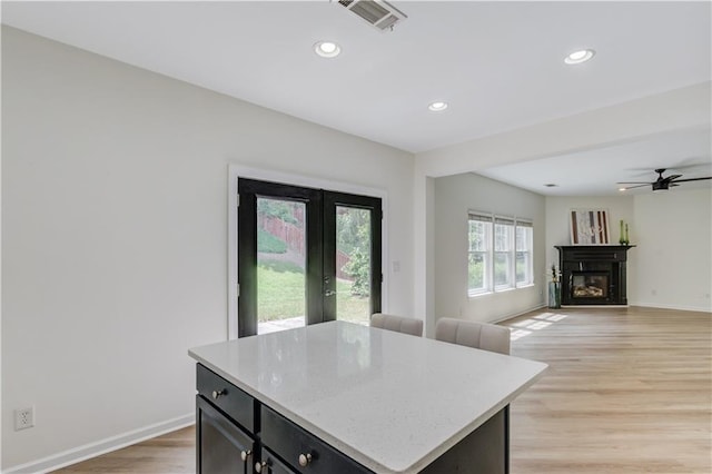 7653 Legacy Rd, Flowery Branch, GA 30542 - kitchen with recessed lighting, light wood-type flooring, baseboards, a glass covered fireplace, and a ceiling fan