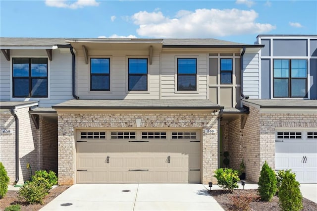 townhome / multi-family property featuring a garage, stone siding, and driveway