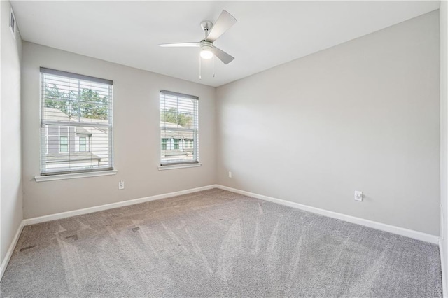 empty room featuring visible vents, carpet flooring, a ceiling fan, and baseboards