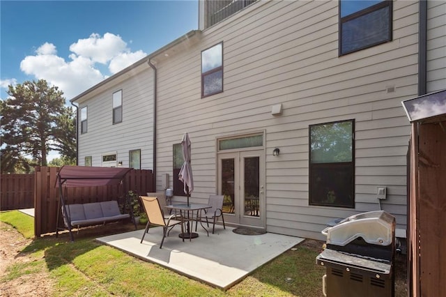 rear view of house with a hot tub, a lawn, fence, french doors, and a patio area