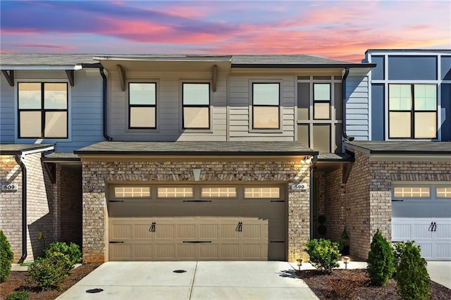 townhome / multi-family property featuring a garage, concrete driveway, and stone siding