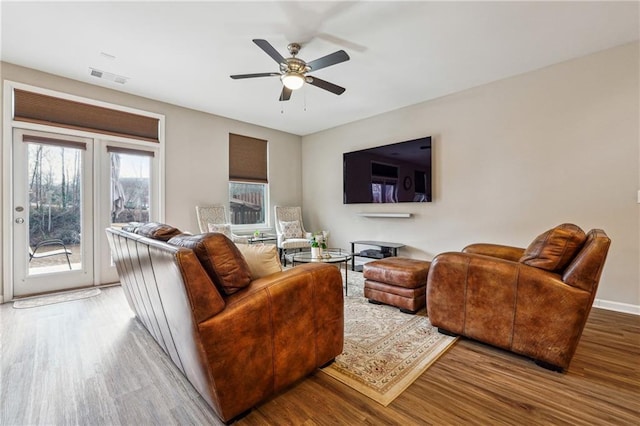 living room featuring a ceiling fan, baseboards, visible vents, and wood finished floors