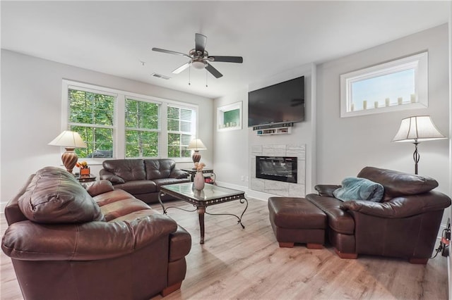 living room featuring ceiling fan, light wood-type flooring, and a fireplace