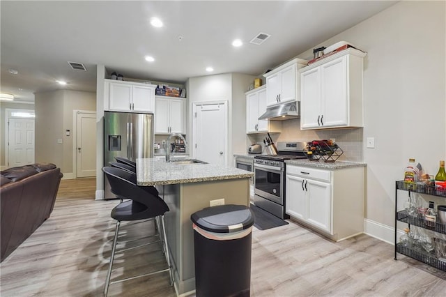 kitchen featuring appliances with stainless steel finishes, sink, a center island with sink, light hardwood / wood-style floors, and white cabinetry