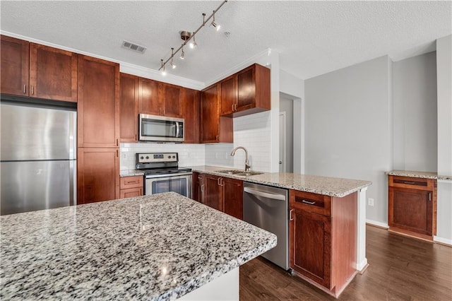 kitchen with sink, stainless steel appliances, light stone counters, dark hardwood / wood-style flooring, and decorative backsplash