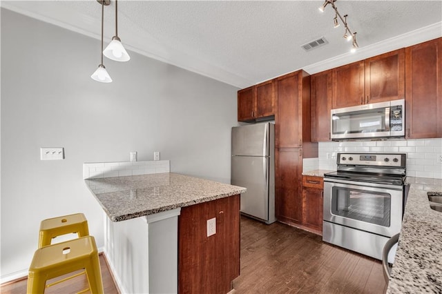 kitchen featuring stainless steel appliances, kitchen peninsula, light stone counters, and decorative light fixtures