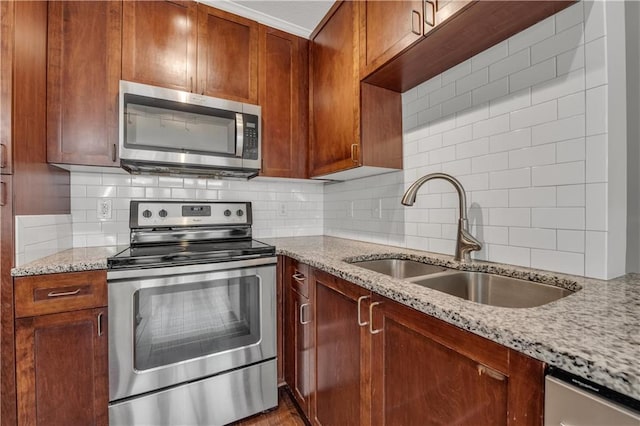 kitchen featuring light stone counters, appliances with stainless steel finishes, sink, and backsplash